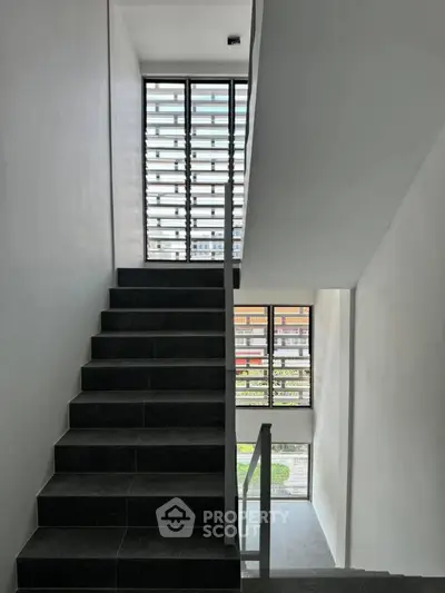 Modern staircase with sleek design and large windows offering natural light