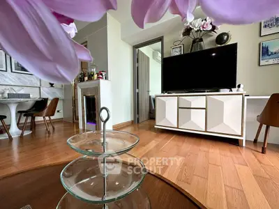 Stylish living room with modern decor and hardwood floors, featuring a sleek TV stand and elegant dining area.