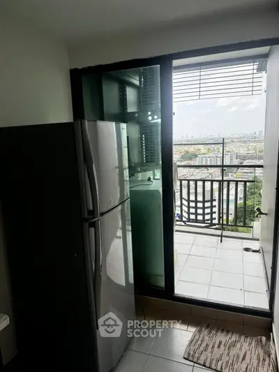 Modern apartment kitchen with balcony view and sleek refrigerator.