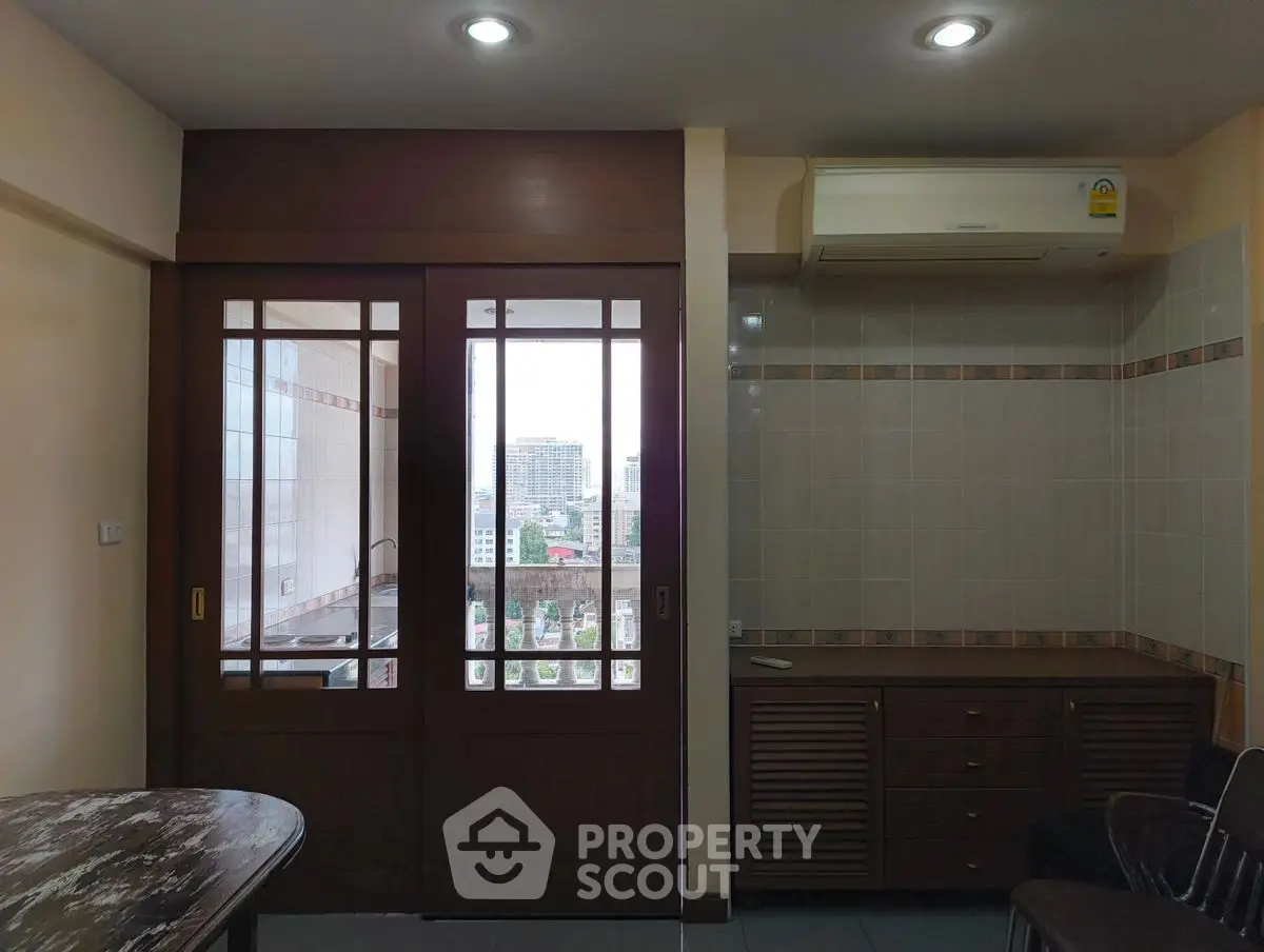Charming interior with sliding doors opening to a city view balcony, featuring air conditioning and tiled walls.