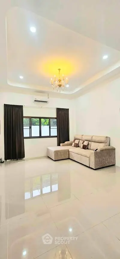Spacious living room with elegant chandelier and modern sofa in a bright, airy setting.