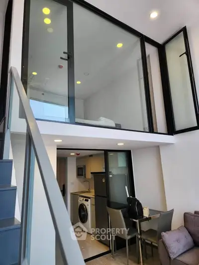 Modern duplex apartment with glass-walled mezzanine and sleek kitchen