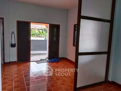 Spacious room with tiled floor and large windows opening to a garden view.