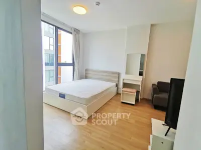 Modern bedroom with large window and wooden flooring in a bright apartment.