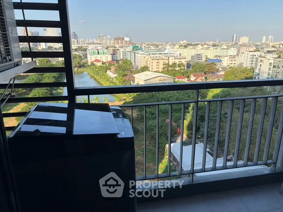 Stunning cityscape view from a high-rise balcony with modern railing and lush greenery.