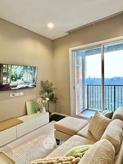 Modern living room with cozy seating and balcony offering stunning city views.