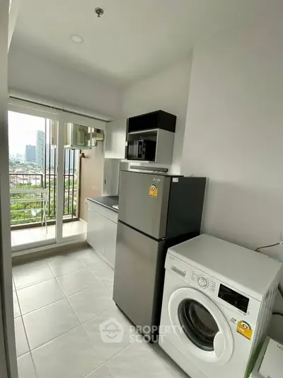 Modern kitchen with balcony view, featuring fridge and washing machine in a sleek apartment.