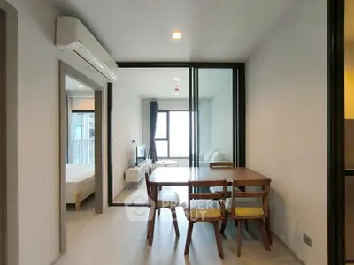 Modern apartment interior with dining area and living room, featuring sleek furniture and natural light.
