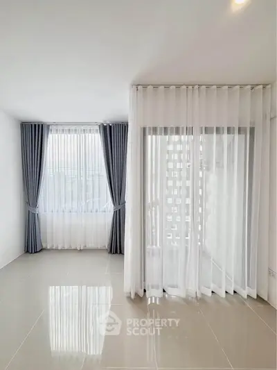 Bright and spacious empty room with large windows and elegant curtains, perfect for customization.