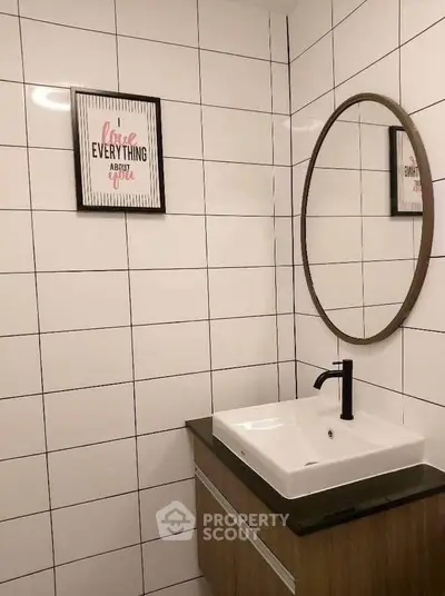 Modern bathroom with stylish mirror and sleek sink in a tiled setting.