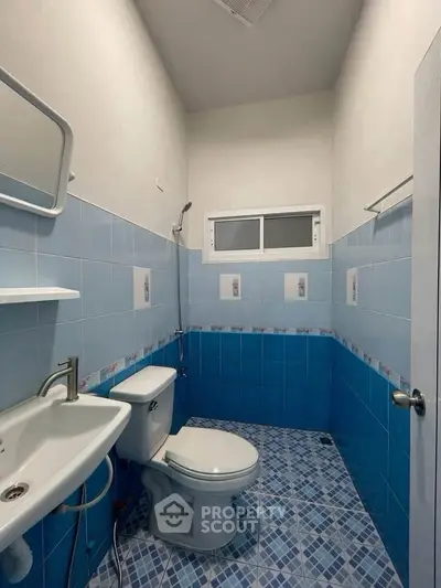 Compact blue-tiled bathroom with modern fixtures and small window