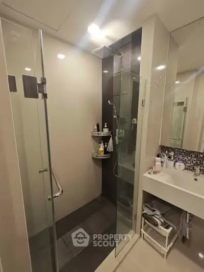 Modern bathroom with glass shower and sleek vanity in contemporary home.