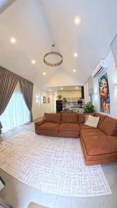 Spacious living room with high ceilings, modern decor, and open kitchen layout.