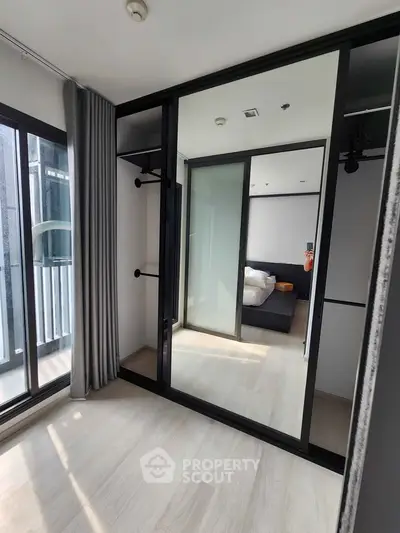 Spacious bedroom with mirrored wardrobe and balcony access in modern apartment