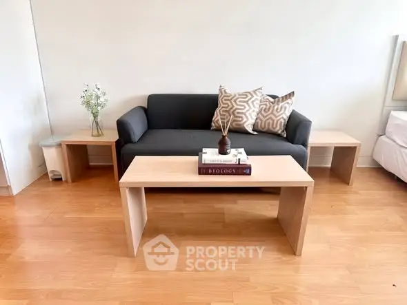 Modern living room with sleek black sofa, wooden coffee table, and stylish decor accents.