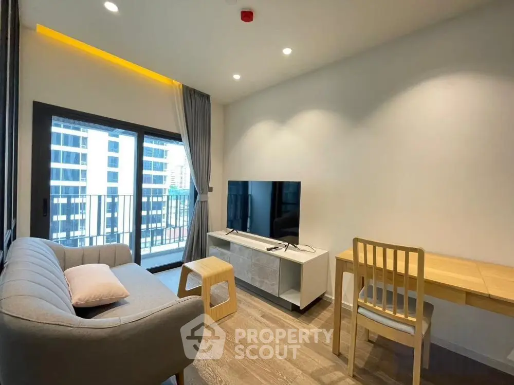 Modern living room with balcony view, featuring sleek furniture and natural light.
