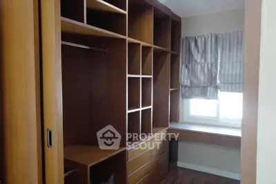 Spacious walk-in closet with wooden shelves and natural light.