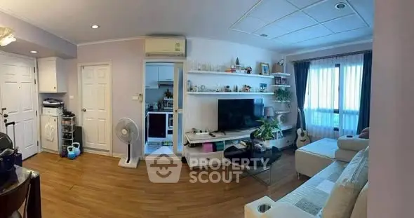 Spacious living room with modern decor and natural light, featuring a cozy seating area and entertainment setup.