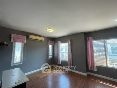 Spacious bedroom with large windows and natural light, featuring modern air conditioning and elegant wooden flooring.