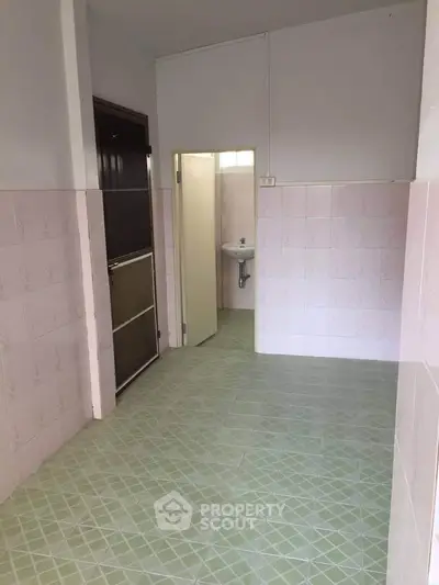 Spacious bathroom with tiled walls and floor, featuring a sink and door.