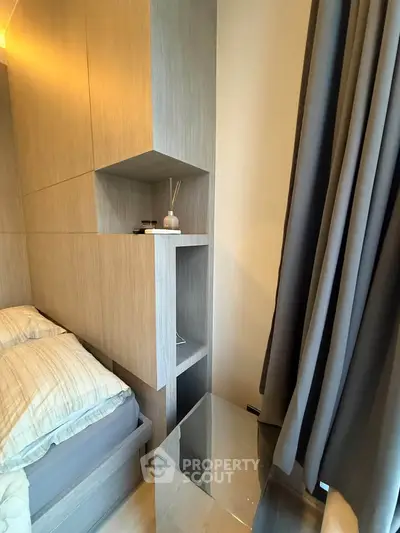 Modern bedroom with sleek wooden storage and cozy bedding, featuring elegant curtains and ambient lighting.
