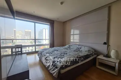 Spacious bedroom with large window offering city views, featuring modern decor and ample natural light.