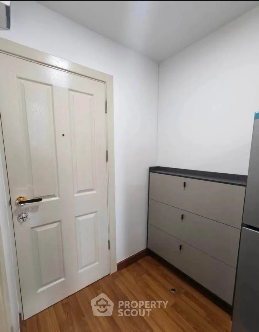 Compact entryway with wooden flooring and storage cabinet