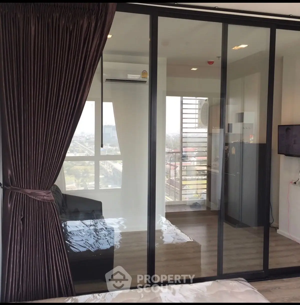 Modern apartment with glass sliding doors and city view, featuring sleek interior design and cozy living space.