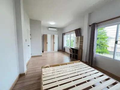 Spacious bedroom with wooden flooring, large windows, and modern furniture.
