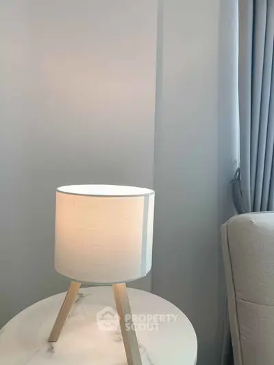 Elegant modern lamp on marble side table in cozy living room corner with soft gray curtains.