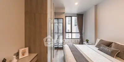 Modern bedroom with stylish decor and city view from window, featuring cozy bed and sleek furnishings.