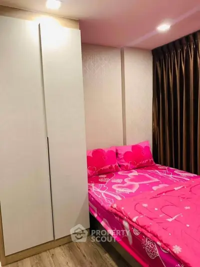 Cozy bedroom with vibrant pink bedding and sleek wardrobe, perfect for a stylish urban living.