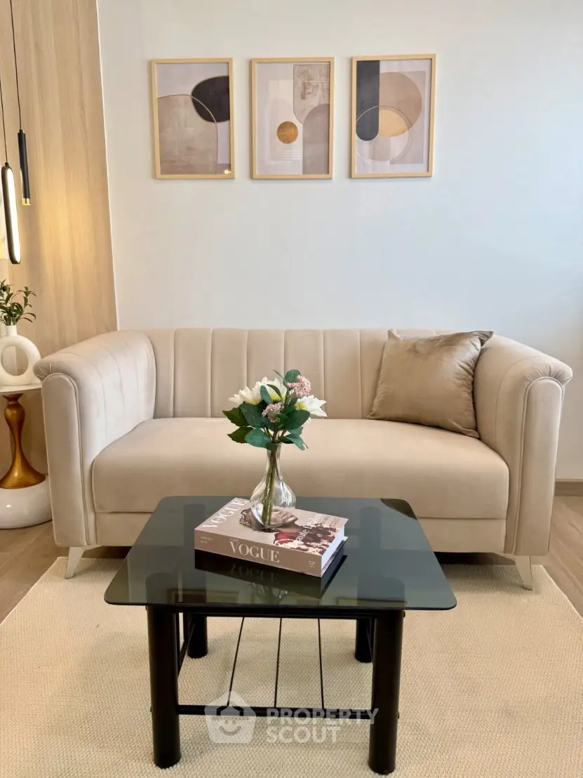 Stylish living room with modern beige sofa, glass coffee table, and elegant wall art.