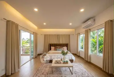 Spacious bedroom with large windows and balcony access, featuring modern decor and lush greenery views.