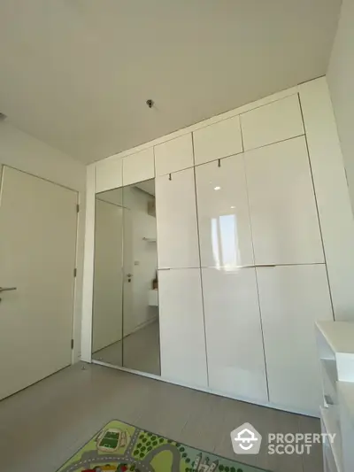 Spacious bedroom with large mirrored wardrobe doors reflecting a modern bathroom, offering a blend of functionality and sleek design in a bright interior.