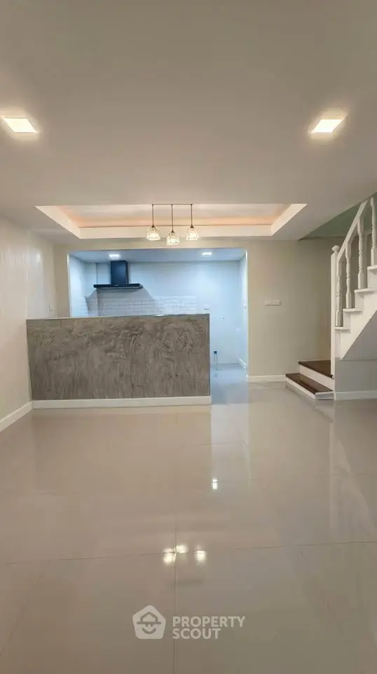 Modern open-plan living room with sleek kitchen and stylish staircase