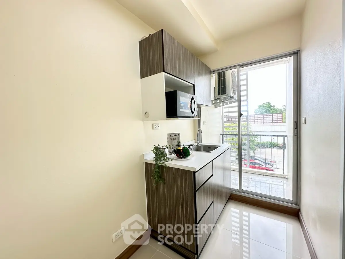 Modern compact kitchen with sleek cabinetry and balcony view