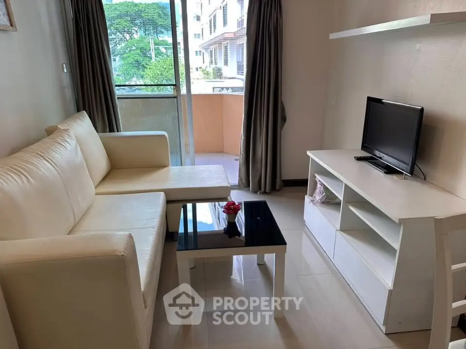 Cozy living room with modern furniture and natural light from balcony view.