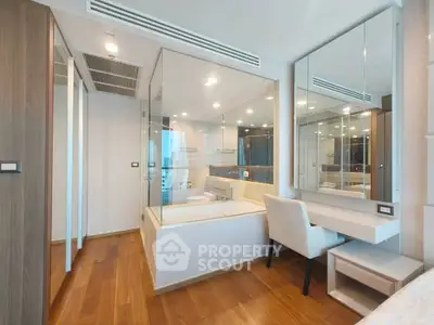 Modern bedroom with glass-enclosed bathroom and wooden flooring