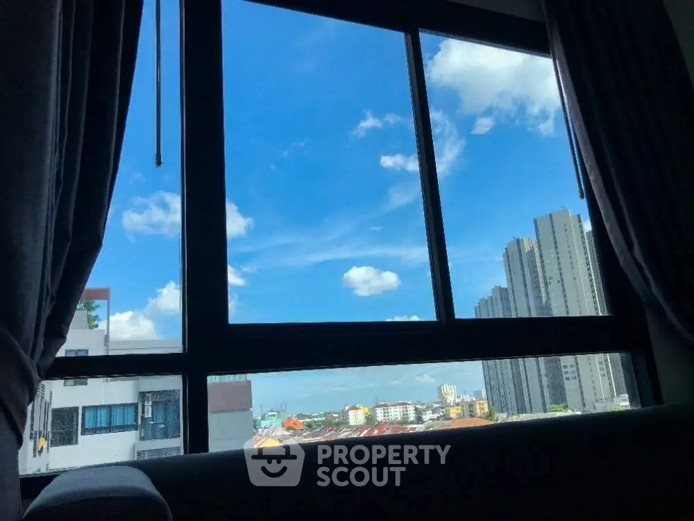 Stunning cityscape view from a modern apartment window with clear blue skies.