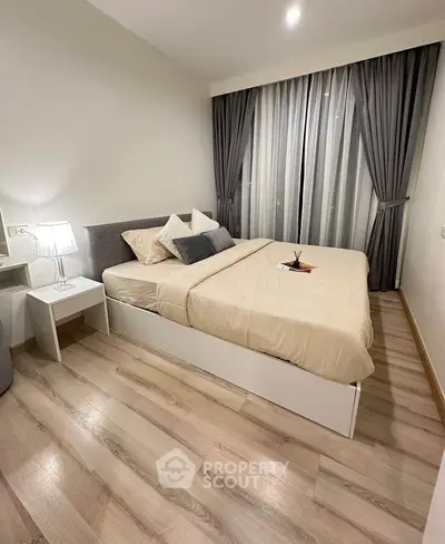 Modern bedroom with elegant decor and large window, featuring cozy bed and stylish curtains.