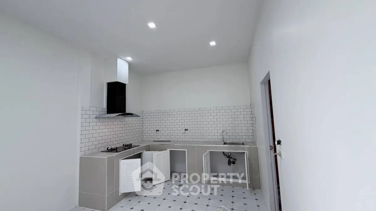 Modern kitchen with sleek white cabinetry and tiled backsplash, featuring a gas stove and ample counter space.