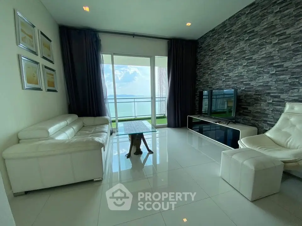Modern living room with stunning sea view, sleek white furniture, and floor-to-ceiling windows.