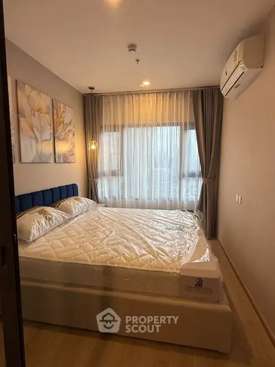 Cozy bedroom with modern decor and large window offering natural light.