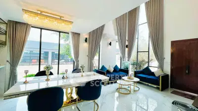 Luxurious modern living room with high ceilings, elegant chandelier, and large windows offering natural light.