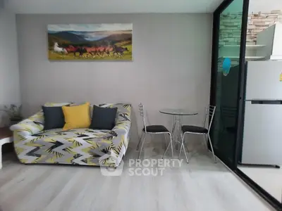 Modern living room with stylish sofa, glass table, and sleek kitchen area.