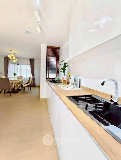Modern kitchen with sleek design and open layout leading to dining area.