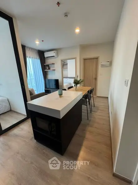 Modern open-plan living room with sleek kitchen island and cozy bedroom view.