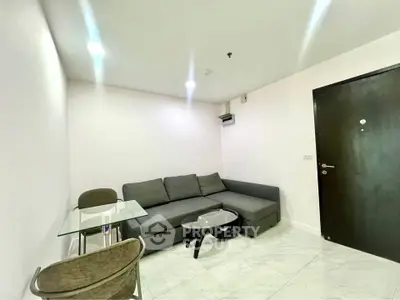 Modern living room with sleek gray sofa and stylish glass table in a minimalist apartment.