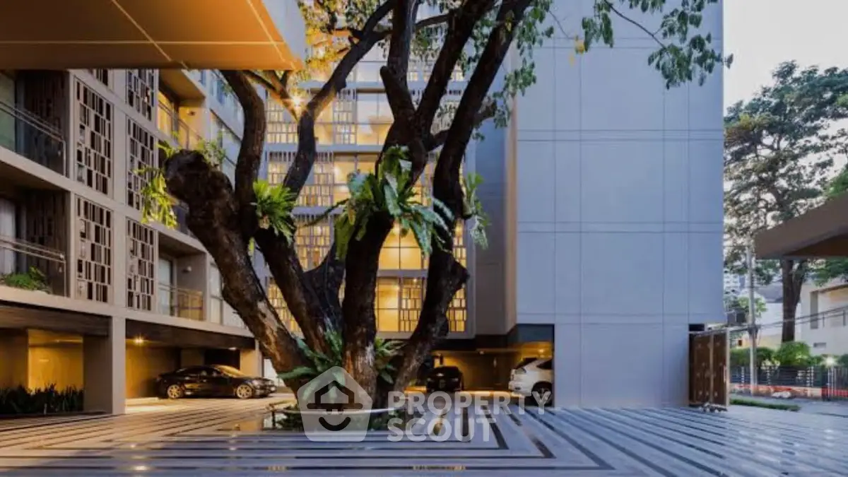 Modern apartment building with spacious parking area and lush greenery.